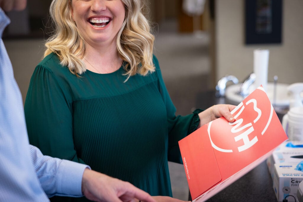 Orthodontist smiling while holding a red folder