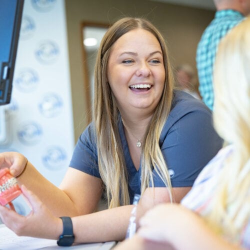 Orthodontic team member showing braces model to patient